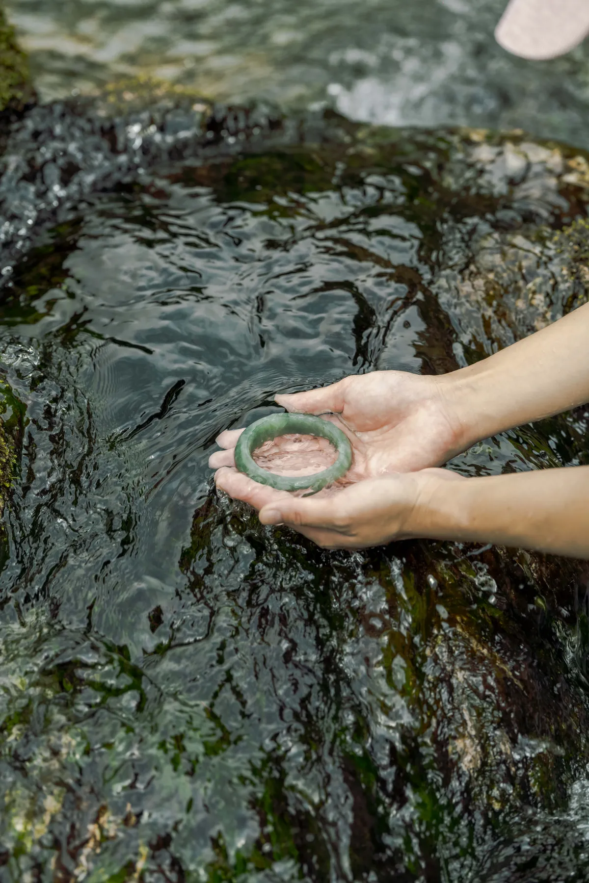 A jade bangle held in the palm by the river