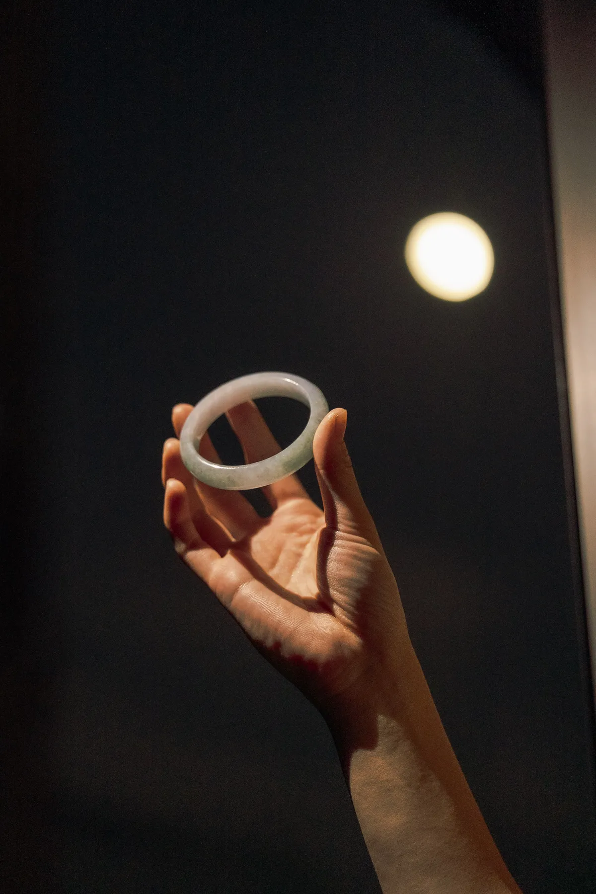 A jade bangle held up to the full moon